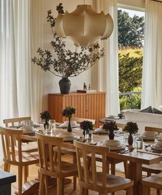 a dining room table set with place settings and flowers in vases on the side