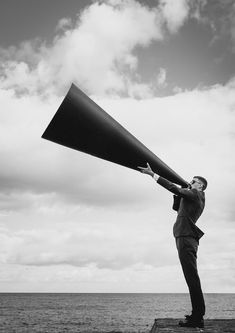 a man in a suit is holding a large object up to the sky with his hands