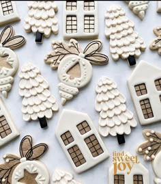 decorated cookies are arranged on a table for christmas time celebrations, including gingerbread houses and trees