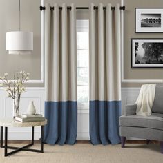 a living room filled with furniture and a window covered in blue and white curtains next to a gray chair