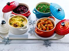 a tray topped with bowls filled with different types of food next to other dishes and utensils