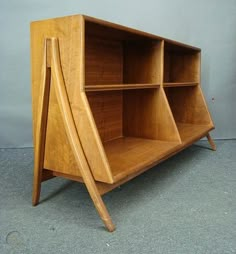 a wooden shelf with three shelves on one side and two open sections on the other