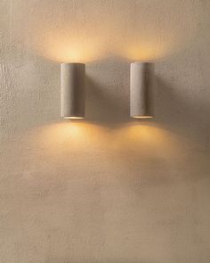 two lights are on the wall in front of a white stucco wall, one is turned off