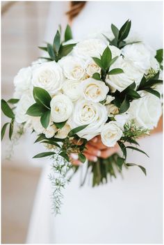 a bride holding a bouquet of white roses