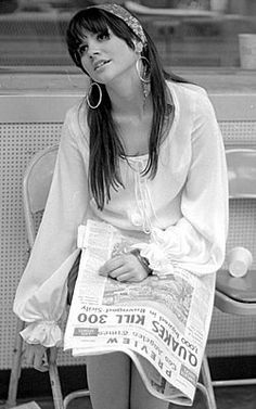 a woman sitting in a chair reading a newspaper