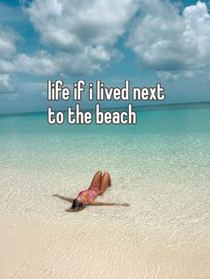 a woman laying on top of a sandy beach under a blue sky with the words life if i lived next to the beach