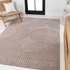 a living room area with a chair and rug on the floor in front of a window