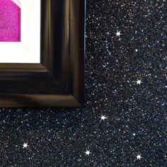 a black frame with a pink and white painting on it's wall next to stars