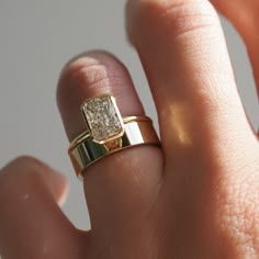 a close up of a person's hand wearing a gold ring with a diamond