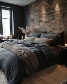 a large bed sitting next to a window with candles on top of it in front of a wooden headboard