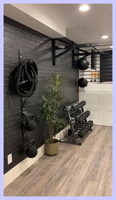 a home gym with black walls and wooden flooring is featured in this image, there are several exercise equipment on the wall