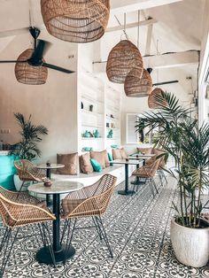 the interior of a restaurant with wicker chairs, tables and plants hanging from the ceiling