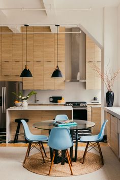 a dining room table with blue chairs in front of an open kitchen and living area