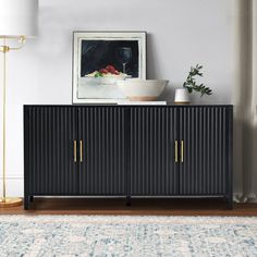 a living room with a rug and a black credenza sideboard in front of a window