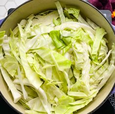 a pot filled with lettuce sitting on top of a stove next to a purple towel