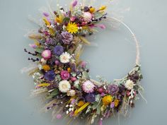 a wreath made out of dried flowers on a gray background with white and yellow accents