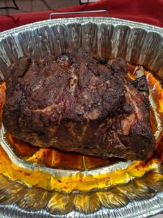 a large piece of meat sitting on top of tin foil in a metal pan with sauce