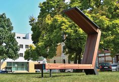 a bench in the middle of a park with trees and buildings in the back ground