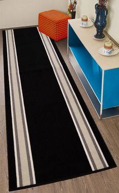 a black and white striped rug on the floor in a living room with blue drawers