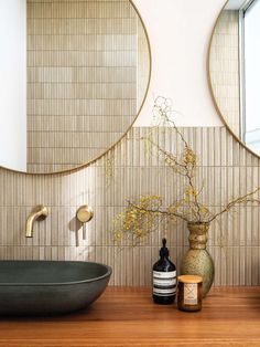 a bathroom with two round mirrors on the wall and a vase filled with flowers next to it