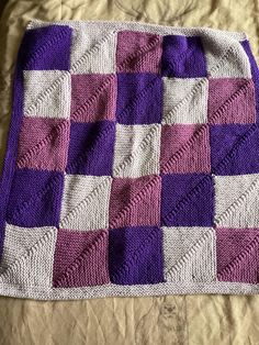 a purple and white blanket on top of a bed