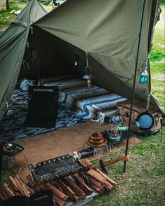 there is a tent set up in the grass with many items on top of it