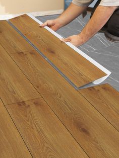 a man laying laminate on top of a wooden floor