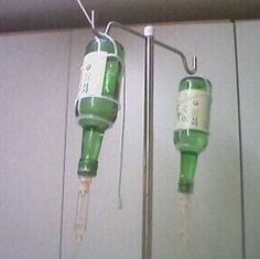 two green glass bottles hanging from a metal hook on a wall next to each other