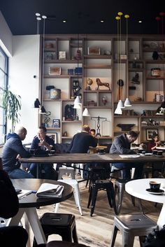 people sitting at tables in a restaurant with lots of shelves on the wall behind them