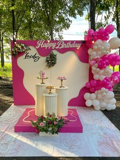 a pink and white birthday party with balloons on the table in front of a sign that says happy birthday lady