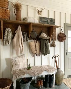 a coat rack filled with coats and hats next to a bench in front of a door