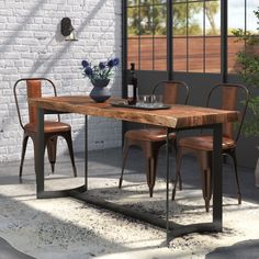 a dining table with chairs and a vase on top of it in front of a brick wall