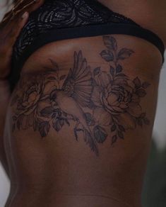 a woman's back with flowers and a bird tattoo on the side of her stomach