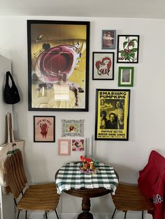 a dining room table with four chairs and pictures on the wall above it, along with several other items