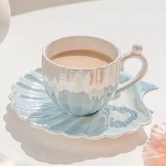 a cup of coffee sitting on top of a saucer next to a pink flower