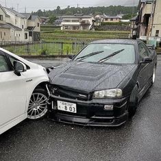 two cars that are parked side by side in the street, one has its hood up