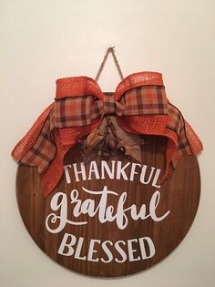 a wooden sign that says, thank grateful and is hung on the wall with a bow