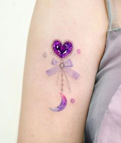 a woman with a tattoo on her arm that has a purple heart and moon hanging from it