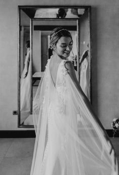 a woman in a wedding dress looking at herself in the mirror with her veil over her head