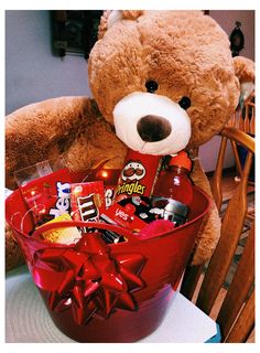 a brown teddy bear sitting next to a red bowl filled with candy and candies