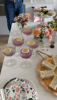 the table is set with glasses, plates and flowers