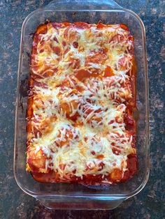 a square casserole dish with cheese and tomato sauce in it on a counter