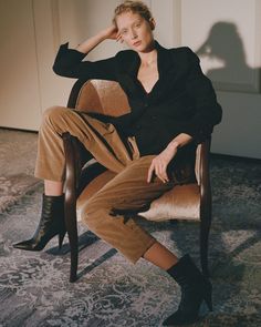 a woman sitting in a chair with her hand on her head and looking at the camera