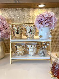 three tiered shelf with vases and cups on it, one filled with flowers