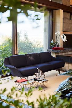 a living room filled with furniture next to a large window covered in lots of greenery