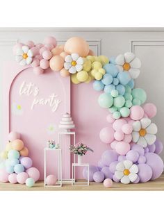 a pink room with balloons and flowers in the shape of an arch, on top of a wooden floor