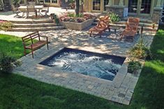 an outdoor hot tub in the middle of a yard with chairs and tables around it