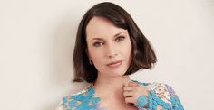 a woman with short hair wearing a blue and white top is posing for the camera