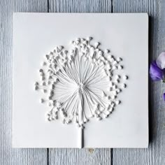 a white card with a flower on it and some purple flowers next to the card