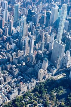 an aerial view of a city with tall buildings and lots of trees in the foreground